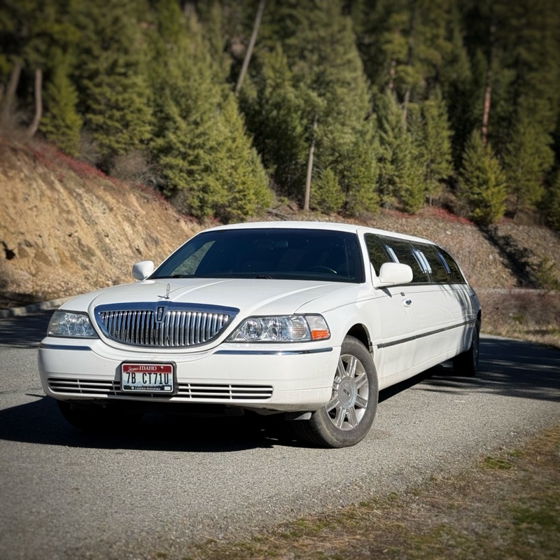The Lockwood Luxury white stretch limousine parked on a forested road in North Idaho